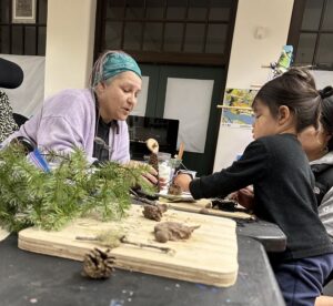 Franc teaching a young child how to create nature-based art.
