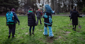 Mesha Florentino, co-executive director of DNDA, walking with Buoy the sea troll, mascot of the Seattle Kraken. Photo by photographer Jamison A. Johnson.