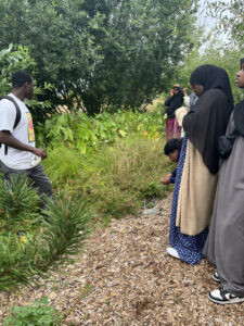 A group of EJ Interns listen closely as Khalil from the Beacon Food Forest explains the site history, and shares more about the plants chosen for the Urban Garden space.