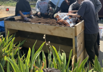 A photo of volunteers adding soil to the accessible garden bed.