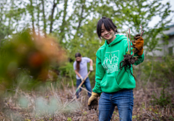 Volunteer holding a plant while working in the field.