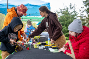 Teaching artists working with volunteers making EcoArt projects at the crafting table.
